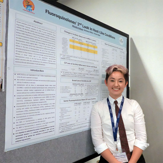 UC San Diego student Mische Holland standing next to their research conference project